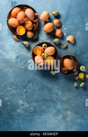 Assortment of raw eggs in wooden dishes. Modern Easter concept with copy space. View from above. Stock Photo