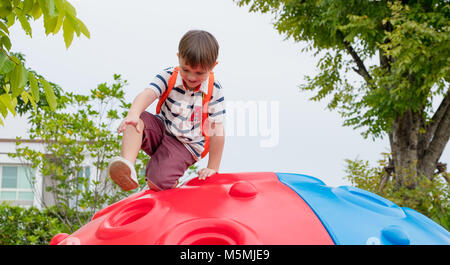 kid boy and backpack having fun to play on children's climbing toy at school playground,back to school outdoor activity. Stock Photo