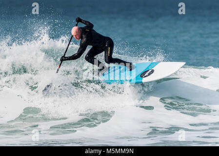 A paddle boarder riding a wave at Fistral in Newquay, Cornwall. Stock Photo