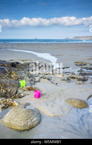 Two brightly coloured plastic buckets left on the beach at Sennen Cove in Cornwall Stock Photo