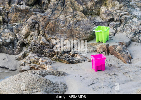 Two brightly coloured plastic buckets left on the beach at Sennen Cove in Cornwall. Stock Photo