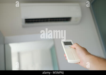 Caucasian man hand with remote control directed on the conditioner Stock Photo