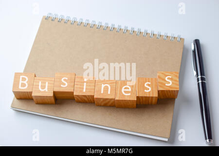 Wood block with business word on Notebook with pen - Business concept Stock Photo