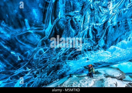 Tourist discovering the ice cave, active traveler man enjoying beauty of a glacial cave, extreme winter vacation, Skaftafell national park, Vatnajokul Stock Photo