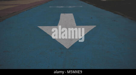Arrow. White arrow on the blue floor. Road sign. Stock Photo