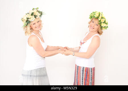 Two blonde women in flower wreaths and dancing and whirling Stock Photo