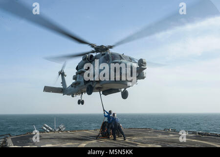 180220-N-VT388-2032 ARABIAN GULF (Feb. 20, 2018) Sailors lift a cargo hook toward an MH-60R Sea Hawk helicopter assigned to the Battlecats of Helicopter Maritime Strike Squadron (HSM) 73, to practice vertical replenishment techniques aboard the guided-missile cruiser USS Bunker Hill (CG 52). Bunker Hill is deployed with the Theodore Roosevelt Carrier Strike Group to the U.S. 5th Fleet area of operations in support of maritime security operations to reassure allies and partners and preserve the freedom of navigation and the free flow of commerce in the region. (U.S. Navy photo by Mass Communica Stock Photo