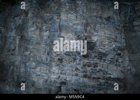 Grunge mystical gray-blue layered rock wall with uneven surface. Stock Photo