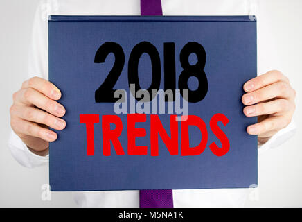 Writing text showing 2018 Trends. Business concept for Trending Data Prediction written on book notebook paper holding by man in suit blurred backgrou Stock Photo