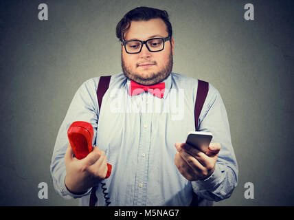 Young man in formal outfit looking puzzled about old fashioned and contemporary gadgets. Stock Photo