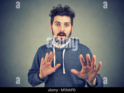 Young bearded man looking at camera with fear and outstretching hands in panic. Stock Photo