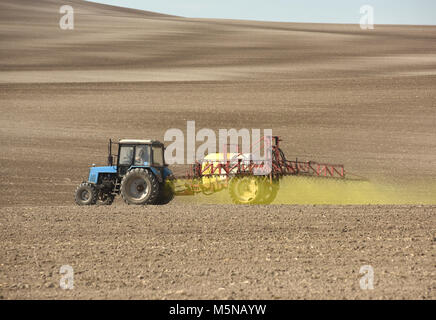 tractor spraying the chemicals on the field. tractor sprinkling pesticides against bugs on agricultural field. Stock Photo