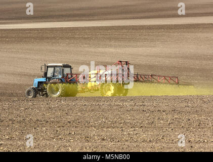 tractor spraying the chemicals on the field. tractor sprinkling pesticides against bugs on agricultural field. Stock Photo