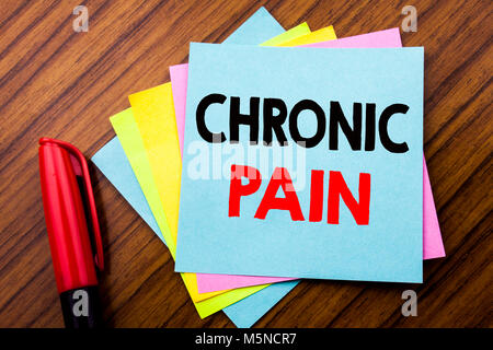 Handwriting Announcement text Chronic Pain.  Concept for Feeling Bad ill Care Written on sticky stick note with wooden background with space office vi Stock Photo