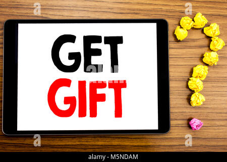 Writing text showing Get Gift. Business concept for Free Shoping Coupon written on tablet computer on wooden background with question mark made of fol Stock Photo