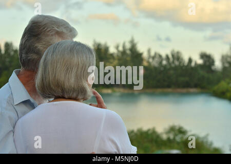 elderly couple standing on sandy beach Stock Photo