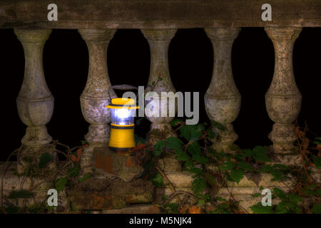 Luminous hand lantern standing near the balustrade of the abandoned restaurant on the top of Mount Akhun at night, Sochi, Russia Stock Photo
