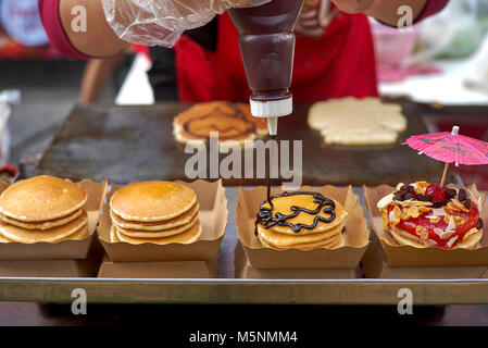 Thailand street food vendor preparing and decorating filled pancakes. Derived From American style  pancakes. 1 of 4 Stock Photo