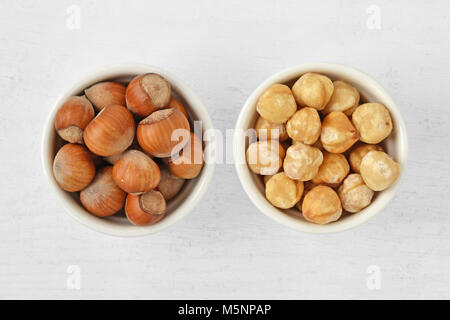 Hazelnuts with and without shell in bowl on wooden background Stock Photo