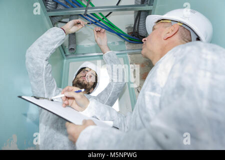 plumber checking ceiling pipes Stock Photo
