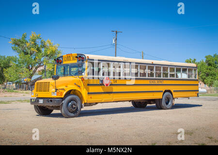 Panorama view of classic tradtional yellow school bus standing on a parking lot on a beautiful sunny day with blue sky in summer in North America Stock Photo