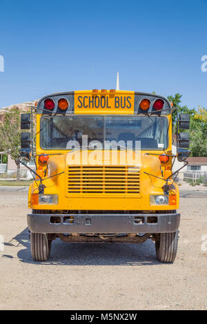 Frontal view of classic tradtional yellow school bus standing on a parking lot on a beautiful sunny day with blue sky in summer in North America Stock Photo