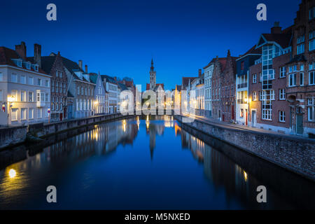 Beautiful panoramic view of famous Spiegelrei canal with famous Poortersloge and Jan van Eyck square in the background illuminated during blue hour at Stock Photo