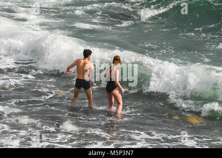 Mousehole, Cornwall, UK. 25th Feb 2018. UK Weather. Sunday was a freezing cold day in Cornwall, with strong winds from the 'beast in the east'. Neverthless this hardy couple decided to strip off and go for a invigorating paddle in the sea. Credit: cwallpix/Alamy Live News Stock Photo