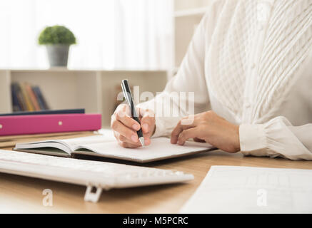 working woman write down appointments or notes meeting schedule for planning works in her office Stock Photo
