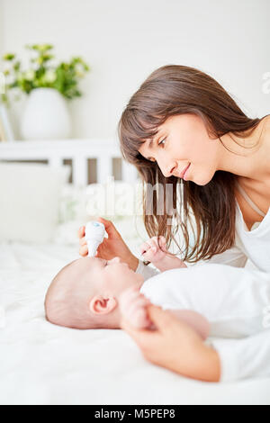 Worried mother measures fever in infant with forehead thermometer Stock Photo