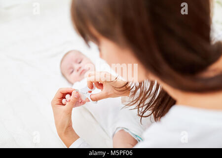 Caring mother carefully cuts her baby's fingernails Stock Photo