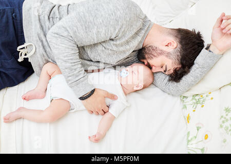 Man as a loving father cuddles up to his little sleeping baby Stock Photo