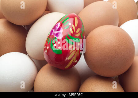 Egg Easter red on the background of unpainted eggs as a symbol began preparing for the holiday Easter. Chicken eggs of different colors of hues close- Stock Photo