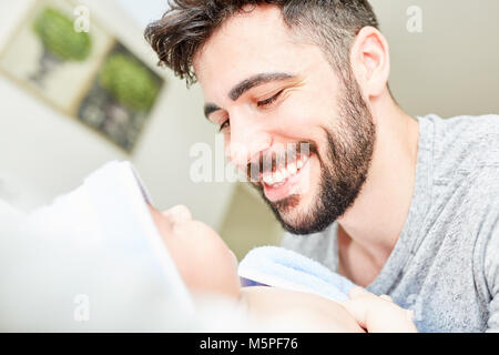 Happy and proud father looks lovingly in the face of his baby Stock Photo
