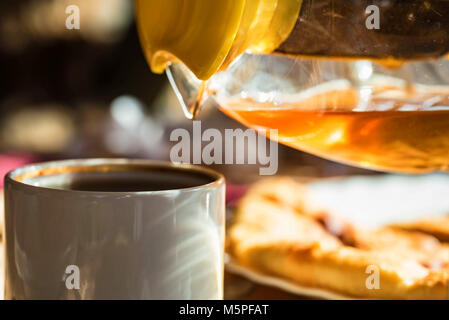 Pouring tea from transparent kettle in cup Stock Photo