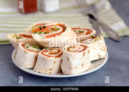 Rolls of thin pancakes with smoked salmon, cream cheese, chives and lettuce. Stock Photo