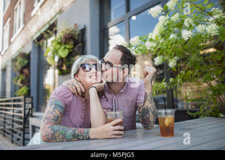 Young couple sitting in outdoor cafe drinking ice tea Stock Photo