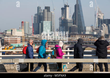 Tourists dressed in winter clothing on a cold clear day, stop to admire the view from Waterloo Bridge over the skyscrapers of City of London, UK Stock Photo