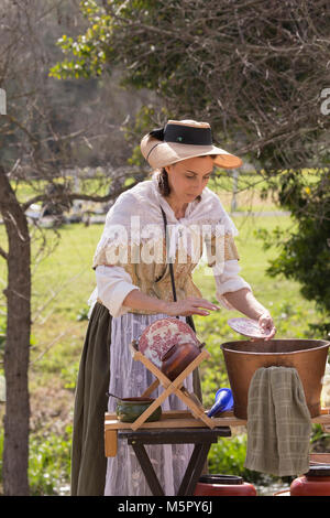 A woman in period dress hand  washing plates and dishes at a American revolution reenactment event in Huntington Beach California USA Stock Photo