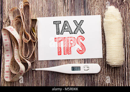 Handwritten text showing Tax Tips. Business fitness health concept writing for Tip Forn Taxes written on wood wooden background with bandage and therm Stock Photo