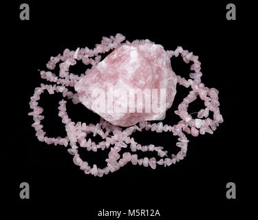 Raw rose quartz from Madagascar and polished rose quartz strings on black background Stock Photo
