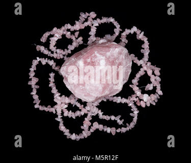 Raw rose quartz from Madagascar and polished rose quartz strings on black background Stock Photo