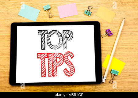 Writing text showing Top Tips. Business concept for Expert Tip Guidance Written on tablet, wooden background with sticky note and pen Stock Photo