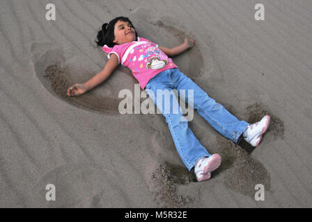Girl making sand angel Stock Photo - Alamy