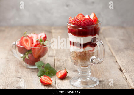 cheesecake with strawberries in a glass on the old wooden background