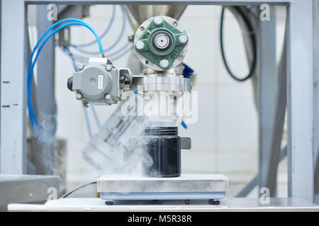 Close-up shot of sport nutrition factory equipment filling in bottle with supplement, blurred background Stock Photo