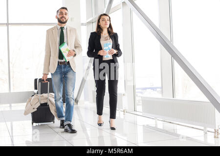 Full length portrait of modern couple holding airplane tickets and suitcase walking to gate in modern airport, copy space Stock Photo