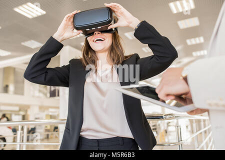 Portrait of modern young woman wearing VR helmet and looking excited enjoying immersive experience Stock Photo