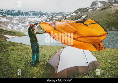 Man adventurer pitching tent camping gear outdoor Travel survival lifestyle concept summer trip vacations in mountains Stock Photo
