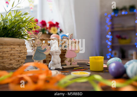 Background image of three Easter bunny figurines on decorated table with basket of eggs, copy space background Stock Photo